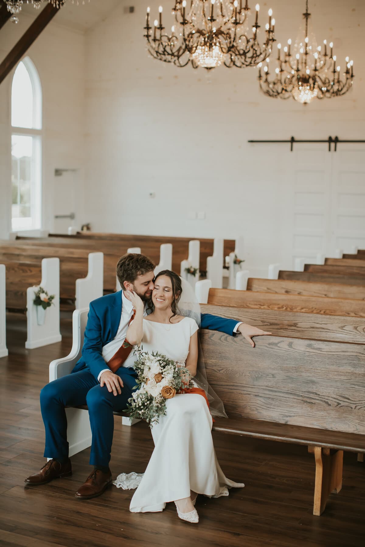 A newlywed couple embracing inside a bright chapel